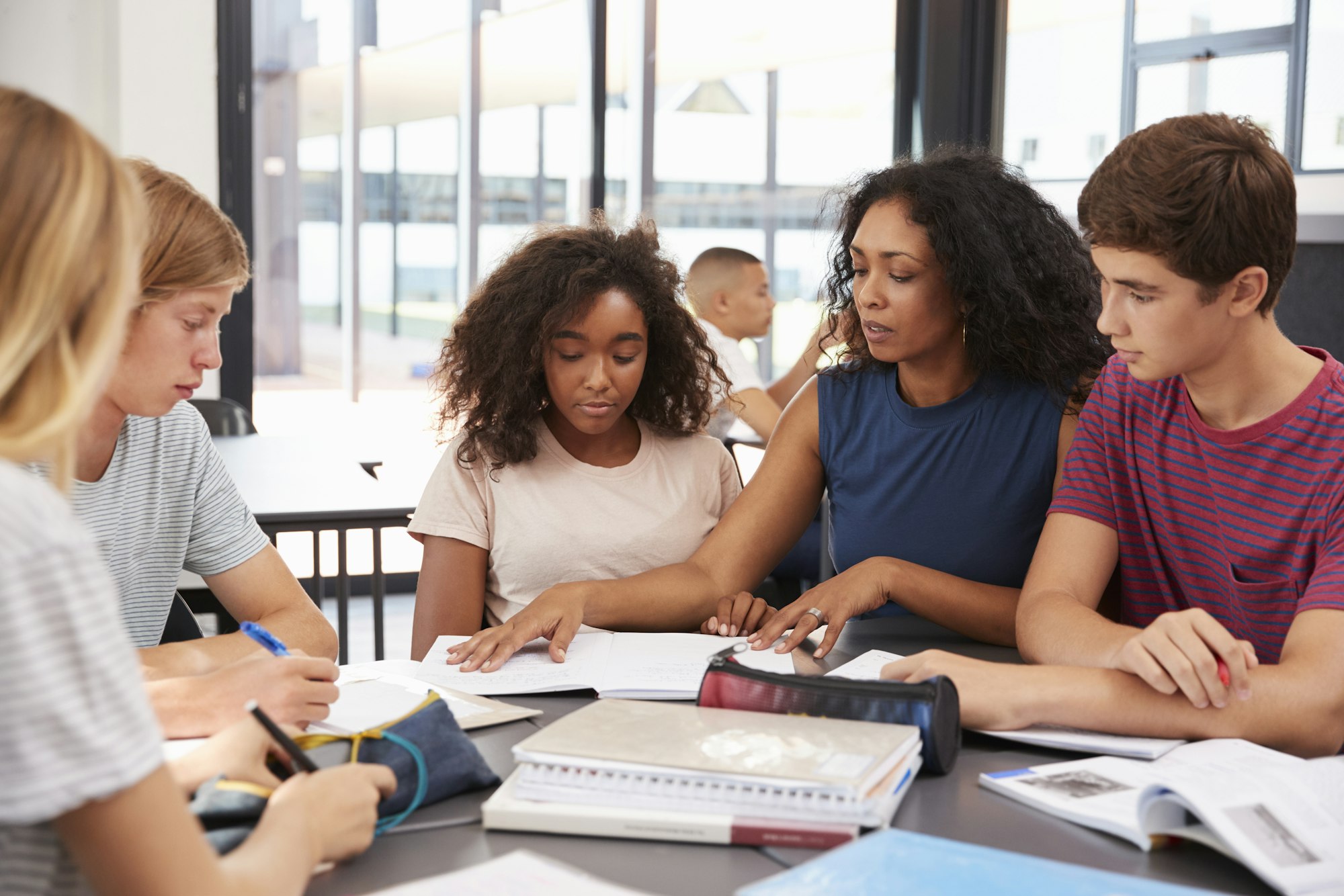 Teacher studying school books in class with high school kids